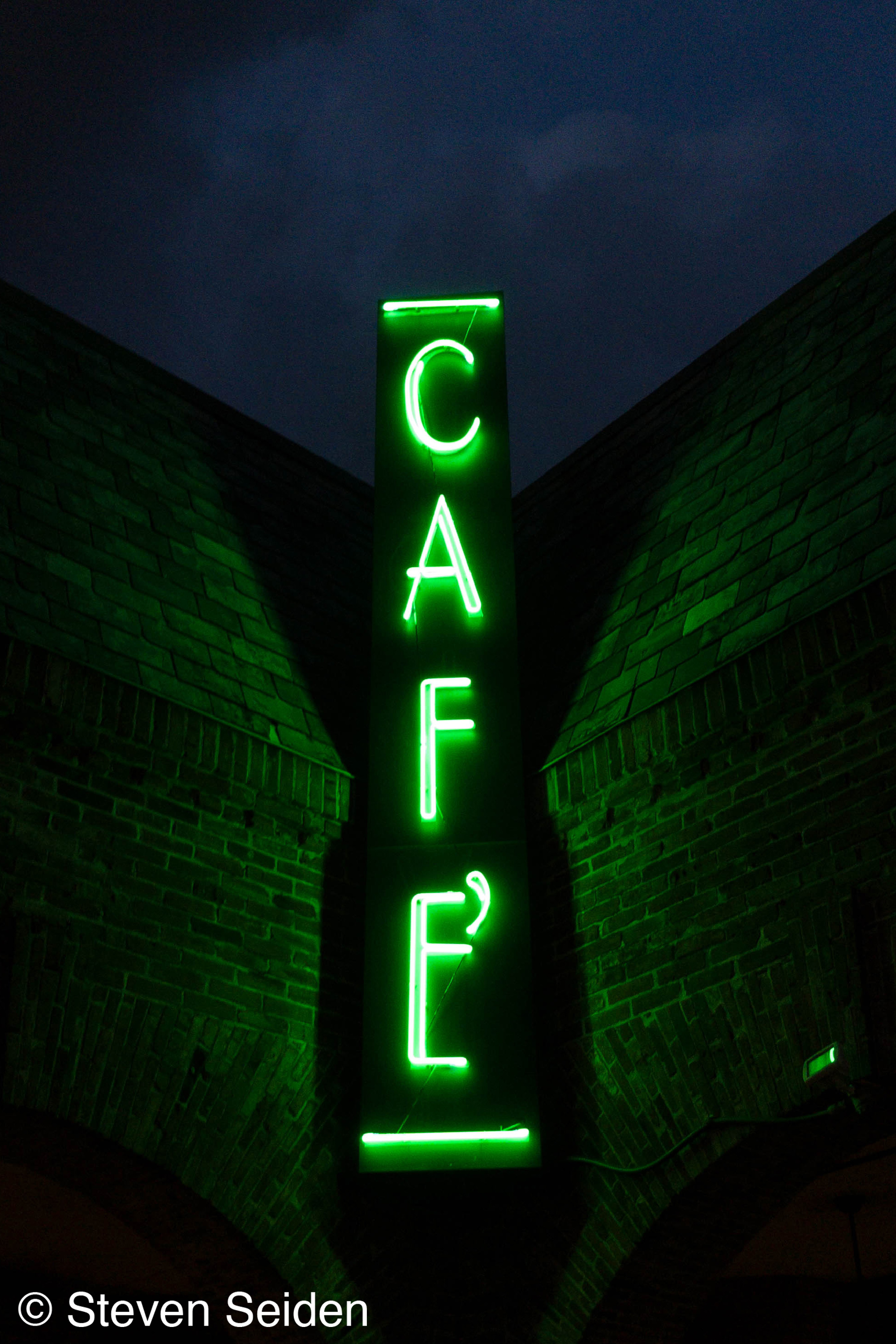 A picture of a neon sign saying 'cafe' taken at night.